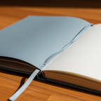 Open notebook with light blue cover on a wooden surface